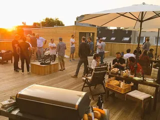 Lots of people that work at 9elements having a nice barbecue at the rooftop terrace in Bochum. The sun is shining and gives off a nice warm natural light.