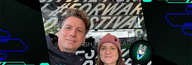Tommi Gutscher und Vanessa Walter stehen vor einem Schild des Forward Festival Wiens und lächeln in die Kamera.