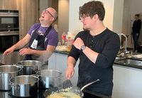 Two men are standing in the kitchen in a good mood and cooking together.